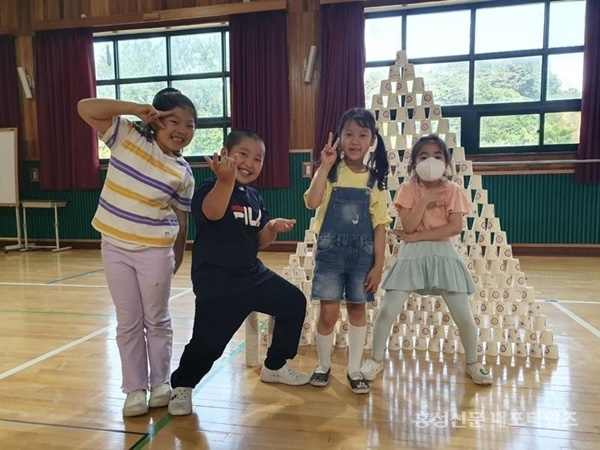 금마초 돌봄교실 놀이체육 프로그램에서 아이들이 종이컵 탑 쌓기 활동을 한 후 포즈를 취하고 있다.<br>